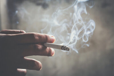 A person holding a cigarette between their fingers.
