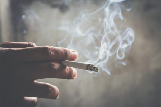 A person holding a cigarette between their fingers.
